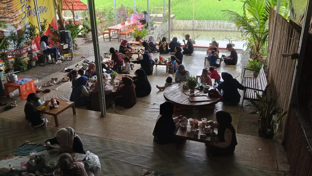Meja lesehan dan tempat duduk menghadap kolam serta sawah